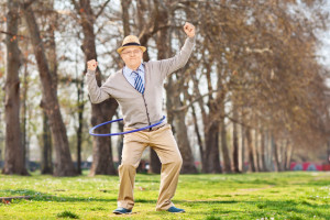 Senior man, exercise with a hula hoop and gesture happiness in park